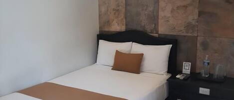 Una habitación de hotel con una cama, mesitas de noche y una pared con diseño que imita a la piedra.