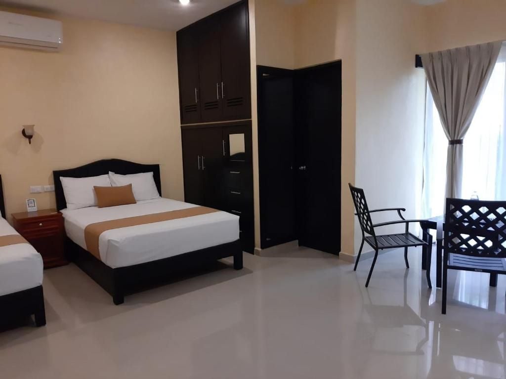 Una habitación de hotel con dos camas, un armario, un escritorio y una silla.