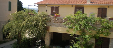 A two-story building with a balcony, a brick base, and a tiled roof.