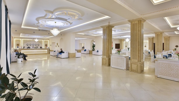 A spacious lobby with a reception desk, seating areas, and decorative columns. - Orient Star Varaxsha (Bukhara)