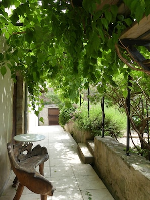A covered outdoor area with a table and chairs, surrounded by greenery and stone walls. - Limoux Riverside Gardens (Limoux)