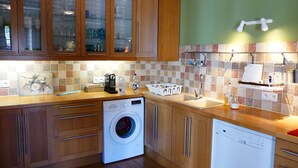 Een keuken met houten kastjes, een wasmachine en een vaatwasser.