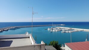 A marina with boats docked, a clear blue sky, and a calm sea. - Orlando Bay View (Balestrate)