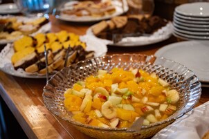 Una mesa de buffet con diversos platos, incluyendo una ensalada de frutas y otros postres.