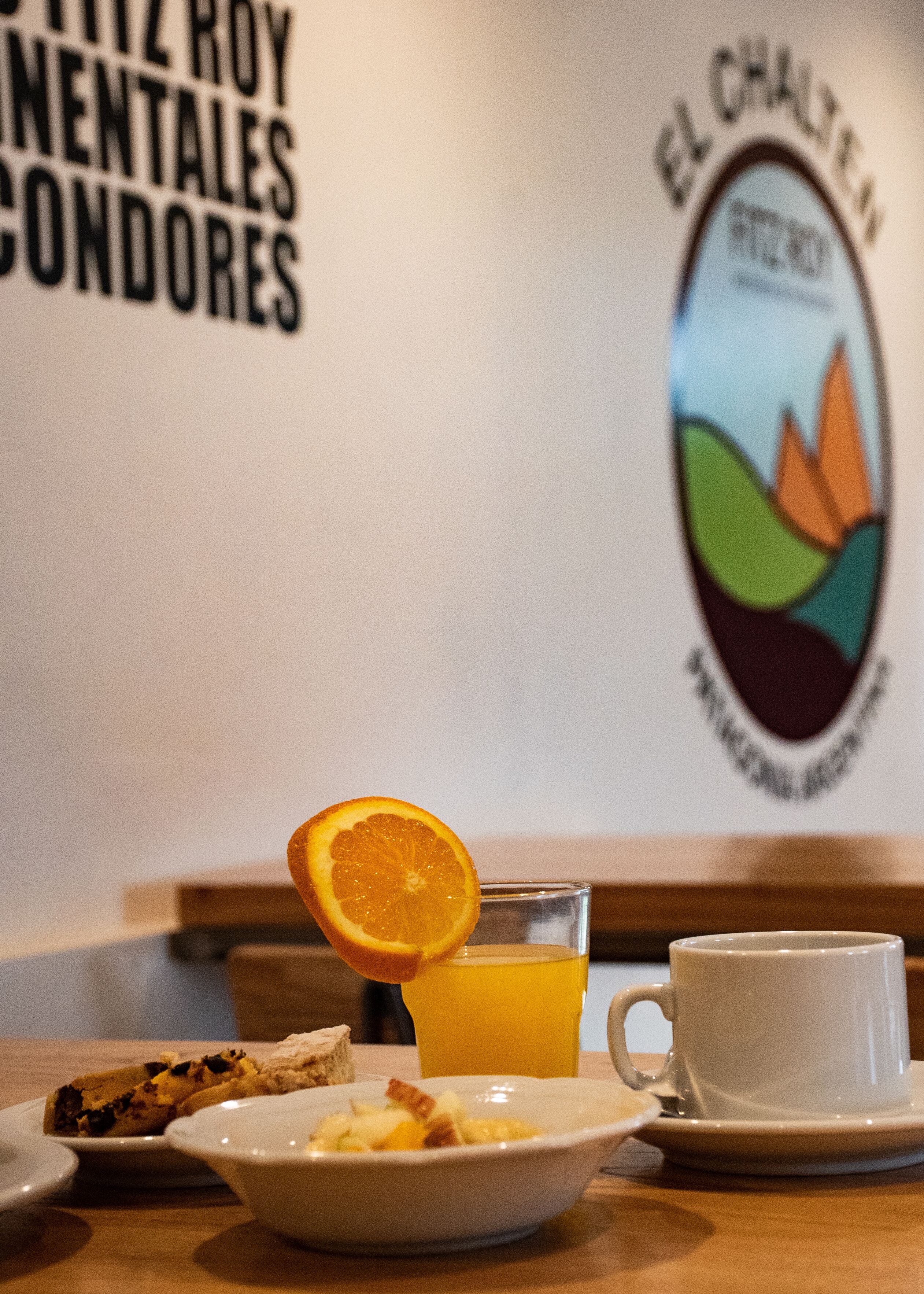 A breakfast setting with a glass of orange juice, a cup, and a bowl of cereal on a table.