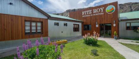 Un hotel llamado 'Fitz Roy Montana' con diseño moderno, destacando una fachada de madera y un techo verde.