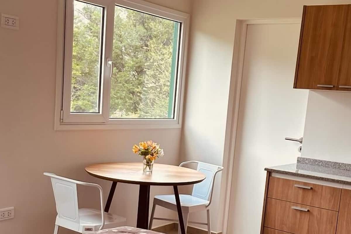 Une chambre à coucher avec un lit, une petite table avec des chaises, une fenêtre et un meuble en bois.
