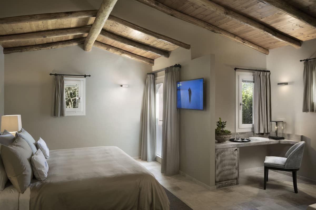 A bedroom with a large bed, a desk, and a TV.