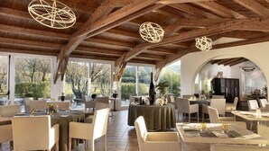 A spacious dining area with high ceilings and large windows, featuring modern lighting fixtures and a variety of seating arrangements. - Li Neuli Country Club (Arzachena)