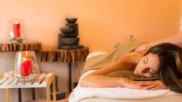 Experience a serene spa setting with a massage table, candle, and soothing ambiance.