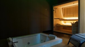 A modern spa room with a large bathtub and a wooden sauna area.