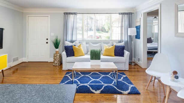 A living room with a white sofa, blue and white rug, and a coffee table. - Light & Airy Family Home (Atlanta)