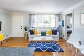 A living room with a white sofa, blue and white rug, and a coffee table. - Light & Airy Family Home (Atlanta)