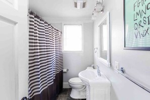 Ein Badezimmer mit gestreiftem Duschvorhang, einem weißen Waschbecken und einer Toilette.