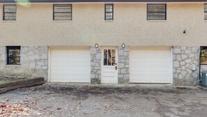 A two-story building with a stone facade and two garage doors. - Light & Airy Family Home (Atlanta)