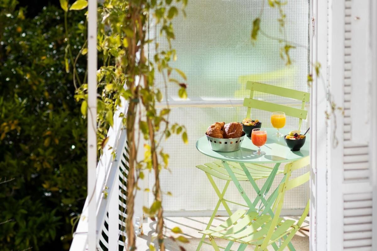 A balcony with a table set for breakfast, including croissants, a bowl of fruit, and a glass of orange juice.
