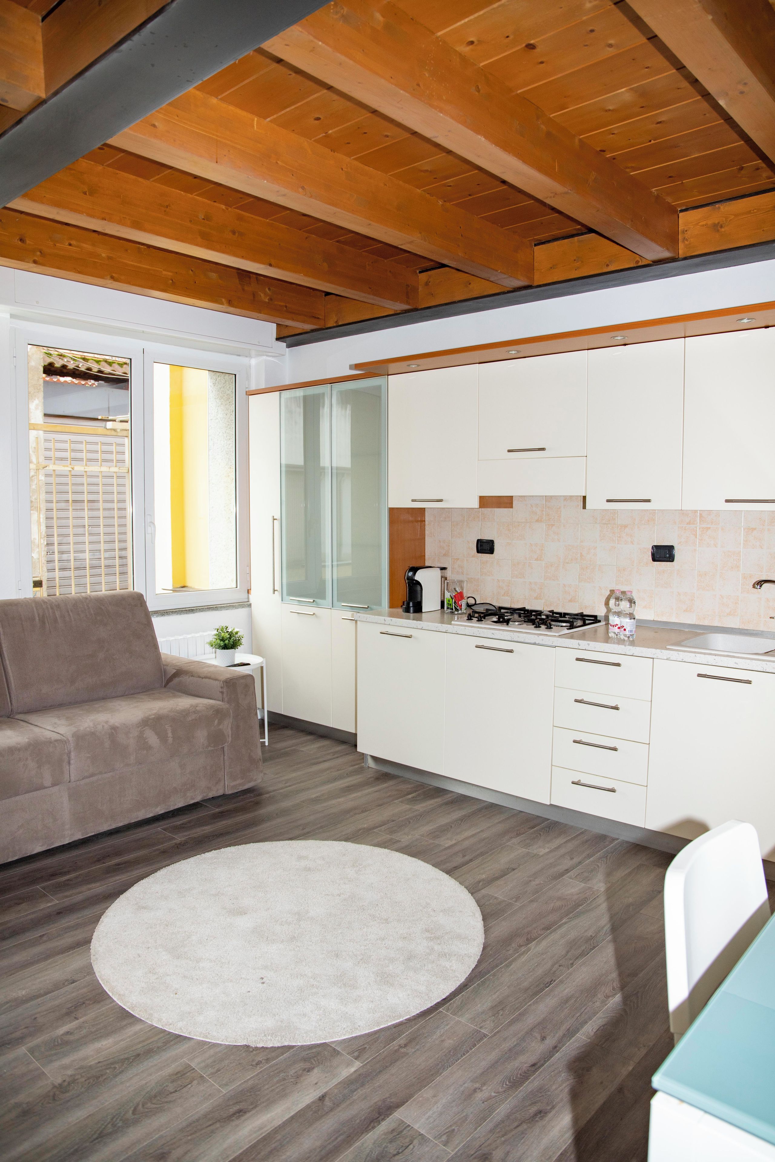 A modern kitchen with white cabinets, a round rug, and a dining area with a table and chairs.