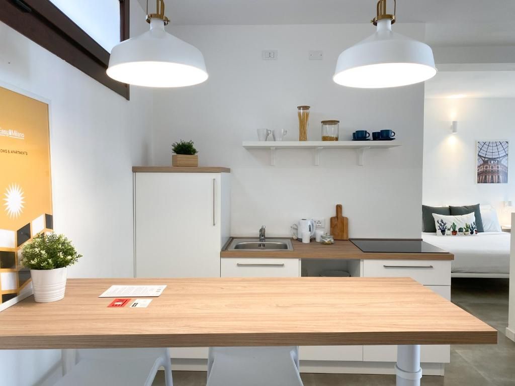 A modern kitchen with white cabinets, a wooden countertop, and pendant lighting.