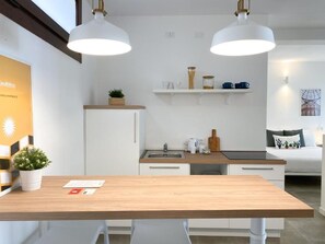 Una cucina moderna con mobili bianchi, un piano di lavoro in legno e luci a sospensione.