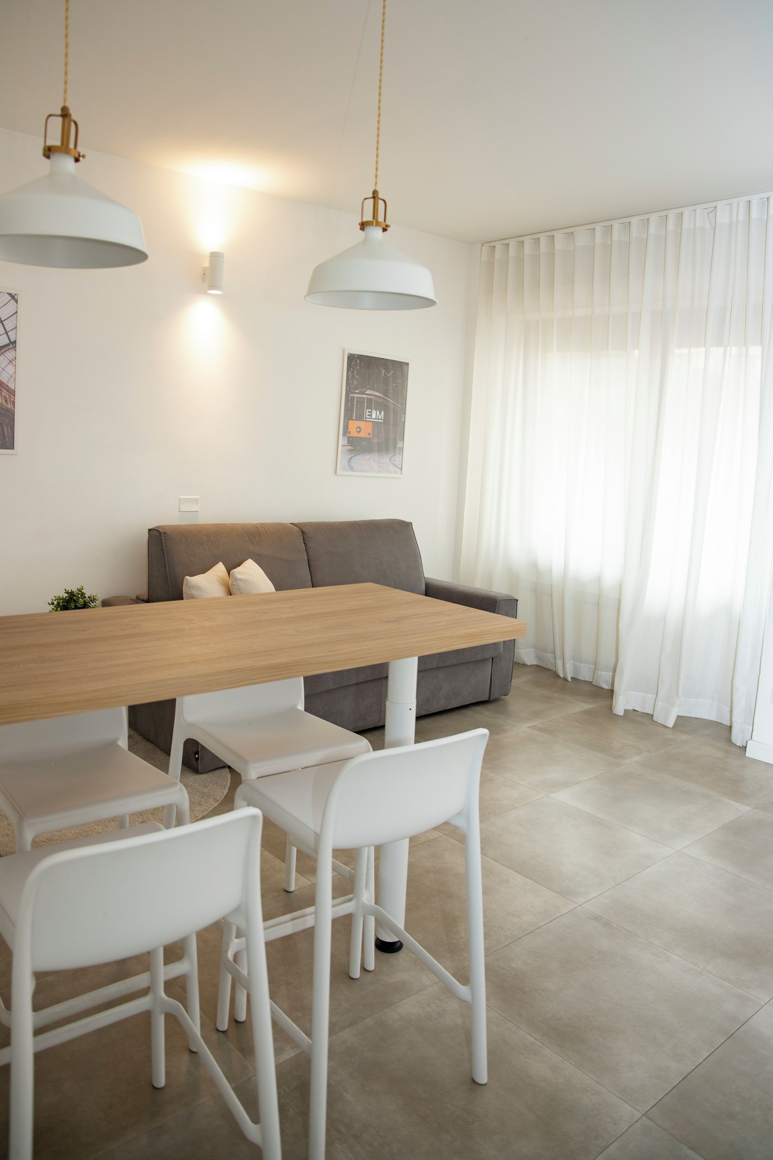 A modern dining area with a wooden table, white chairs, and pendant lighting.
