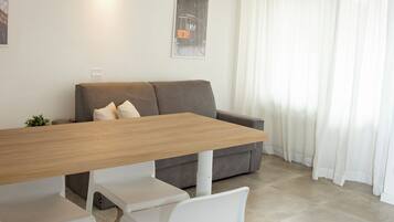 A modern dining area with a wooden table, white chairs, and pendant lighting.
