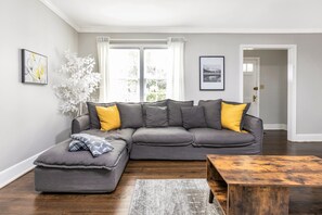 A modern living room with a grey sectional sofa, a wooden coffee table, and a grey rug.