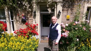 A man standing in front of a building with a sign indicating a 4-star rating. - Averon  Guest House (Edinburgh)