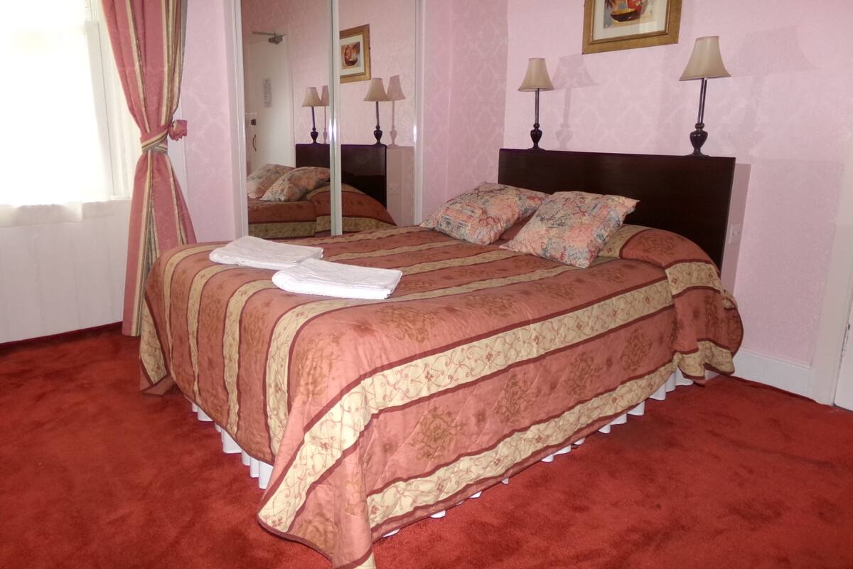 Un dormitorio con una cama grande, dos lámparas de noche, un espejo y un cuadro en la pared.