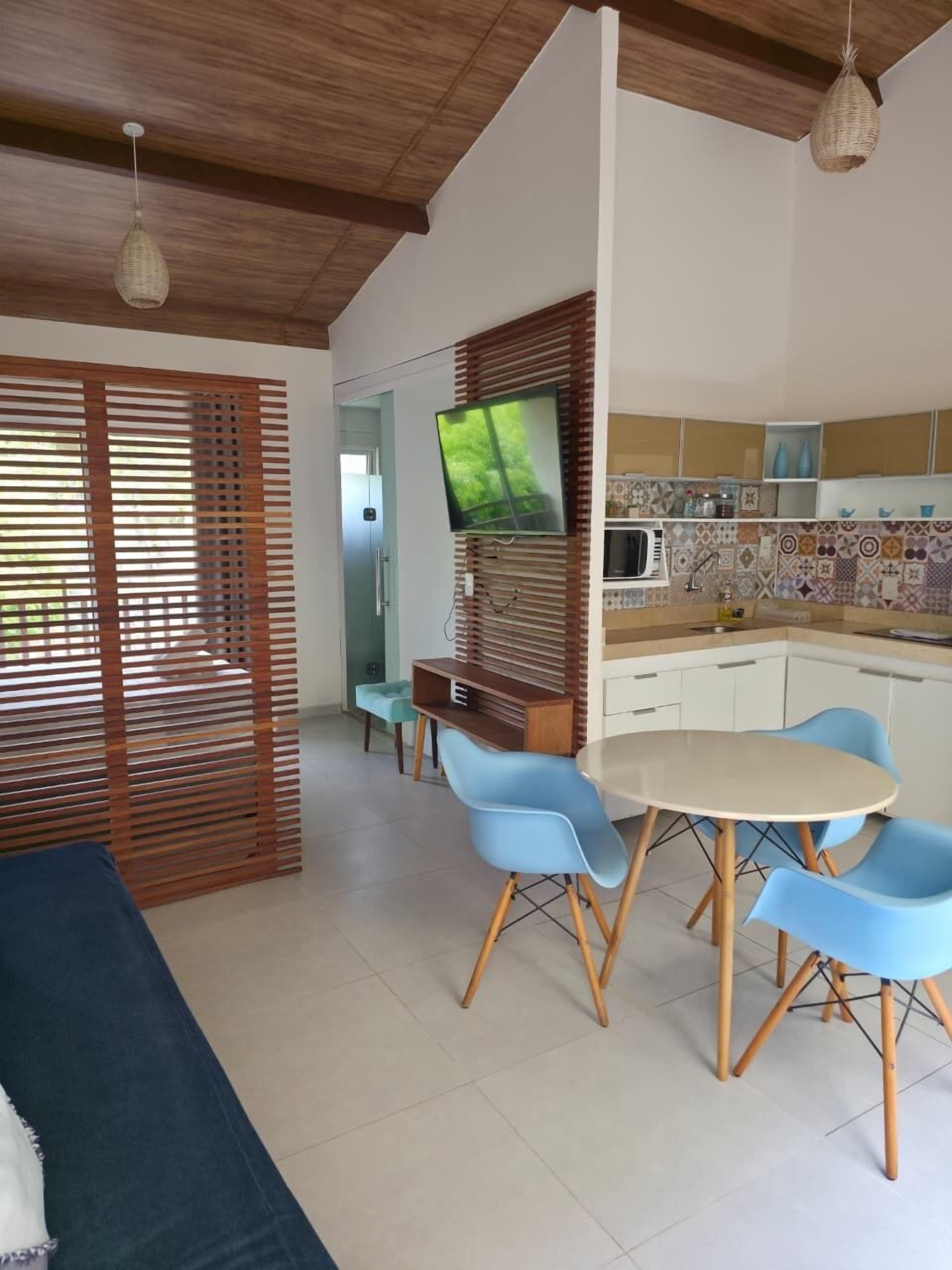 Una cocina moderna con comedor, techo de madera y televisor en la pared.