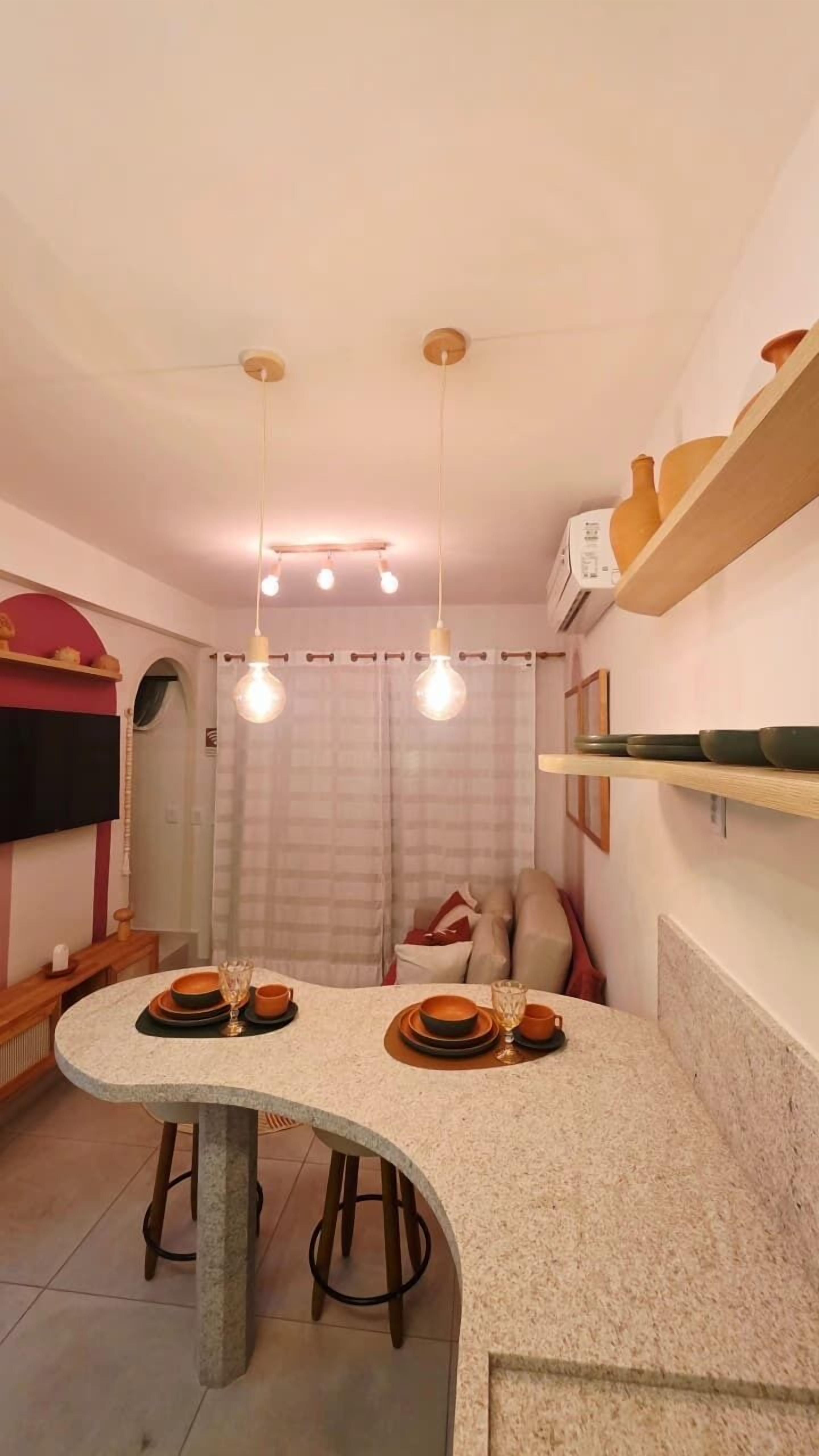 A compact kitchen with a curved island, pendant lighting, and a dining area.