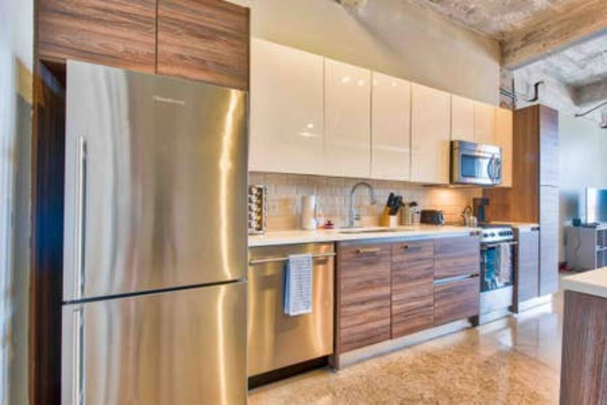 A modern kitchen with stainless steel appliances, wooden cabinets, and a microwave.