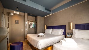 Une chambre d’hôtel avec deux lits, un petit coin salon, une armoire et une salle de bain.