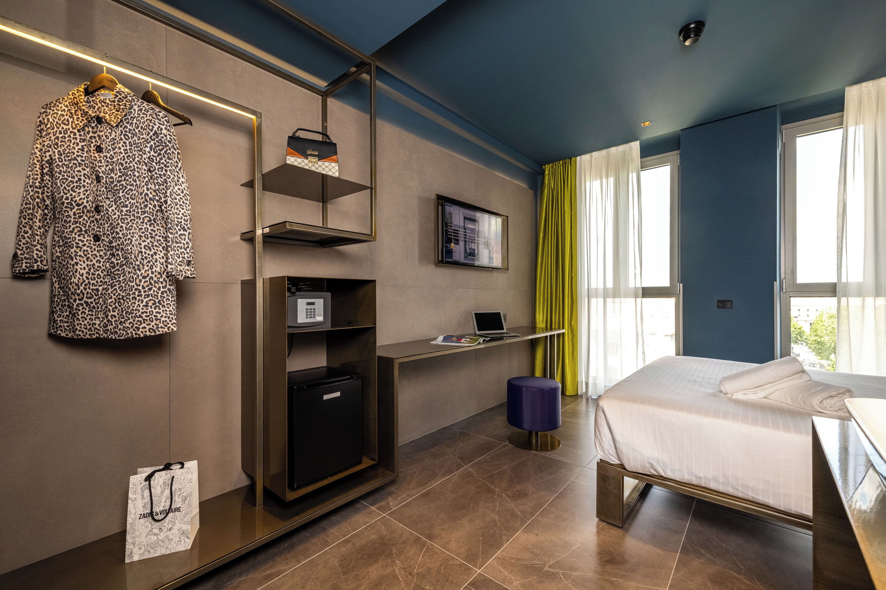 A modern hotel room with a bed, a desk, a wardrobe, and a TV.
