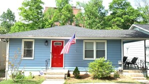 Een woonhuis met een rode deur, een Amerikaanse vlag en een kleine voortuin met een pad.