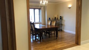 Un comedor con una mesa y sillas de madera, una araña y un aparador de vidrio con objetos decorativos.