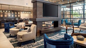 A modern lounge area with a large flat-screen TV, comfortable seating, and a large window offering a view of the outdoors. - Residence Inn Scottsdale Salt River (Scottsdale)
