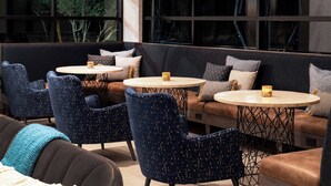 A modern lounge area with dark blue upholstered chairs, round tables, and a leather sofa. - Residence Inn Scottsdale Salt River (Scottsdale)