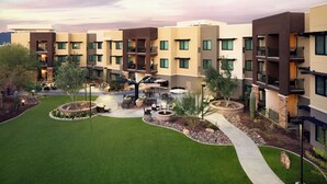 A multi-story residential building with balconies, a landscaped courtyard with seating, and a fire pit. - Residence Inn Scottsdale Salt River (Scottsdale)