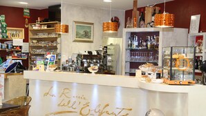 A bar area with a counter, shelves with bottles, and a menu board. - B&B La Roccia dell'Elefante (Castelsardo)