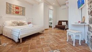 A bedroom with a bed, bedside table, and a chair. - B&B La Roccia dell'Elefante (Castelsardo)