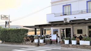 A restaurant with outdoor seating, a signboard, and a view of the countryside. - B&B La Roccia dell'Elefante (Castelsardo)