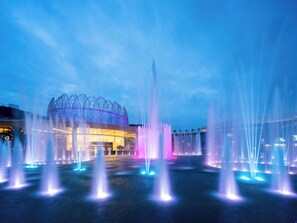 A modern building with a unique dome structure and a fountain display.