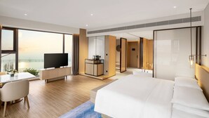 Een moderne hotelkamer met een groot bed, een bureau met een televisie, en uitzicht op een brug.