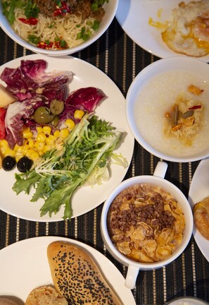 A table with various dishes including noodles, salad, soup, and bread.