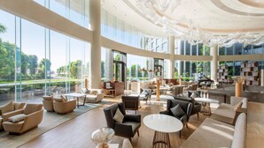 Een ruime lobby met modern meubilair, grote ramen en uitzicht op groen.