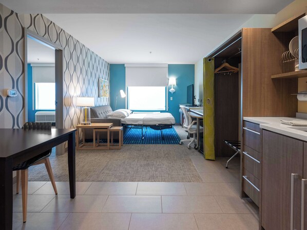 Una habitación de hotel moderna con cama, escritorio y kitchenette.