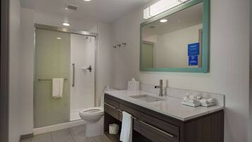 Een moderne badkamer met een douchecabine van glas, een wit toilet, een wastafel met spiegel en een badkamermeubel met lades en een handdoekhouder.