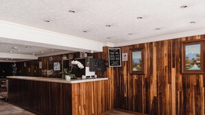 A reception area with a wooden reception desk, a sign listing room rates, and framed pictures on the wall. - Hotel Rex (Toluca)