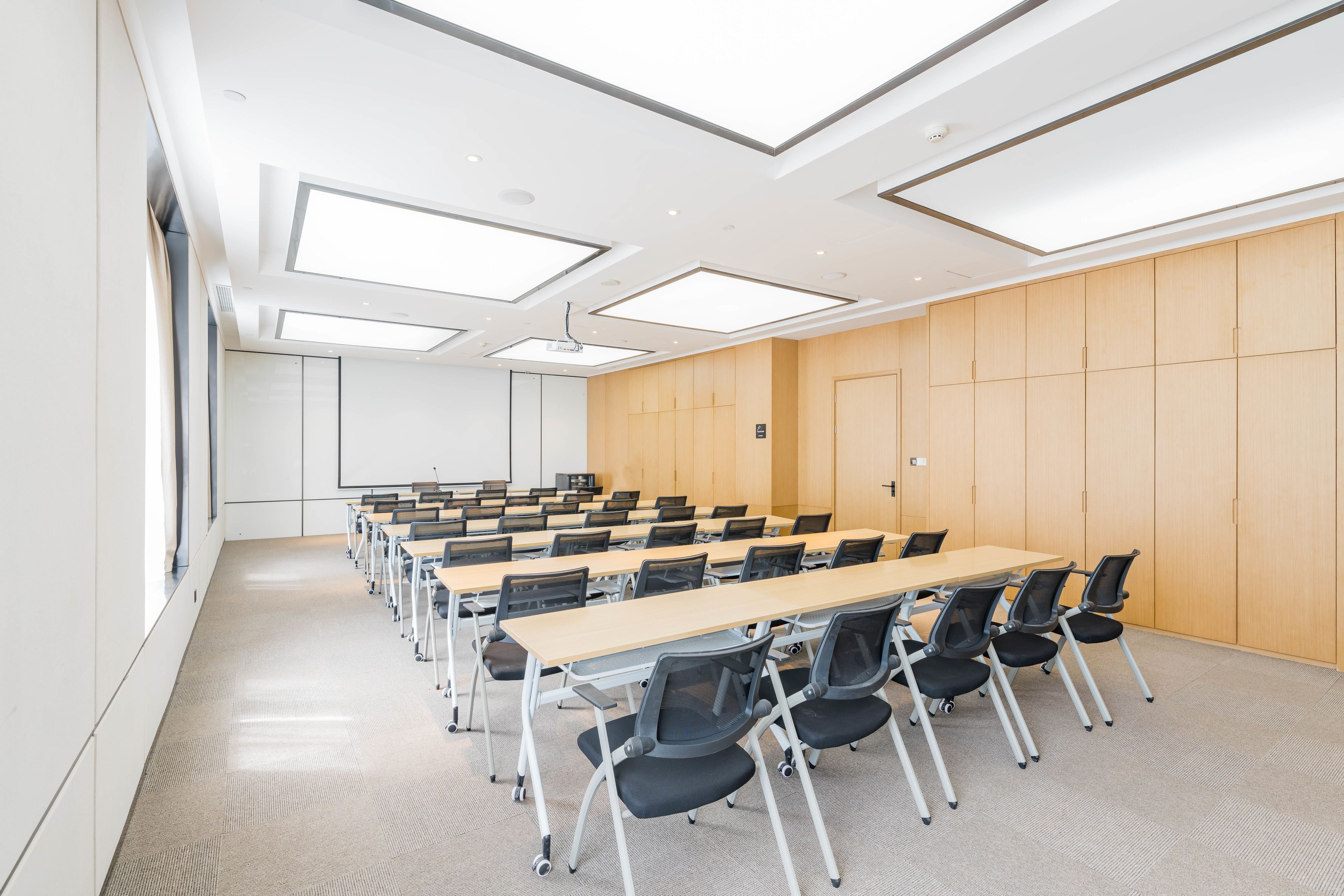 Un salón de conferencias con una larga mesa, sillas y un revestimiento de madera.
