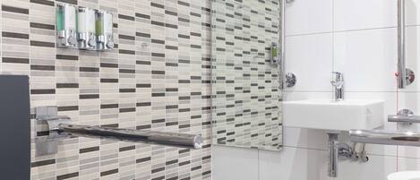 A modern bathroom with a tiled backsplash, a mirror, a toilet, and a sink.